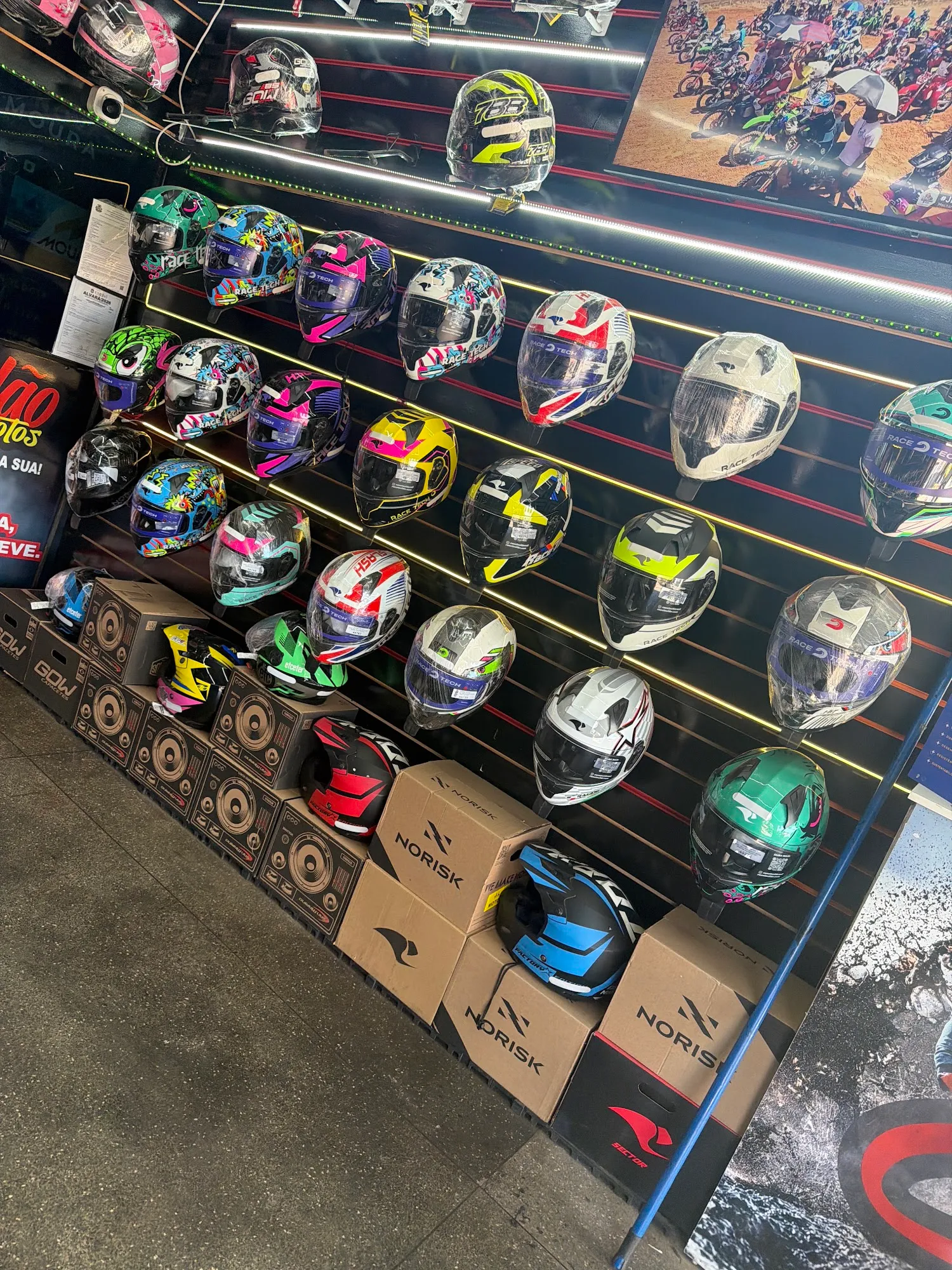 Parede de capacetes coloridos iluminada por LED na loja de moto peças